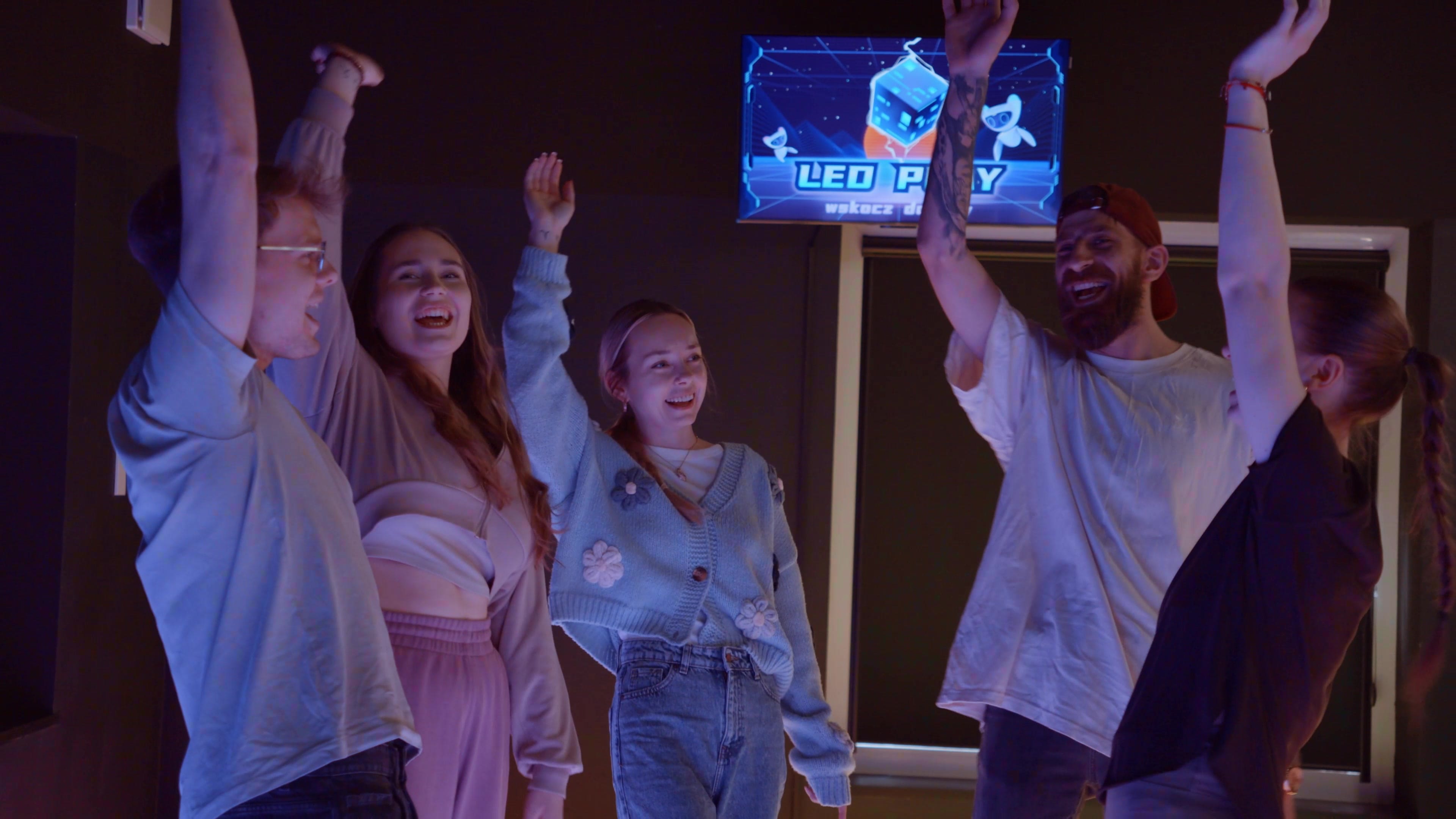 Dzieci świętują z rękami w górze na podłodze pixelowej w LEDPlay mini – interaktywna podłoga LED
